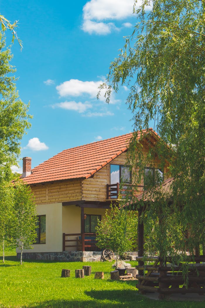 Home Discover a picturesque rustic house surrounded by vibrant greenery in a serene summer landscape.